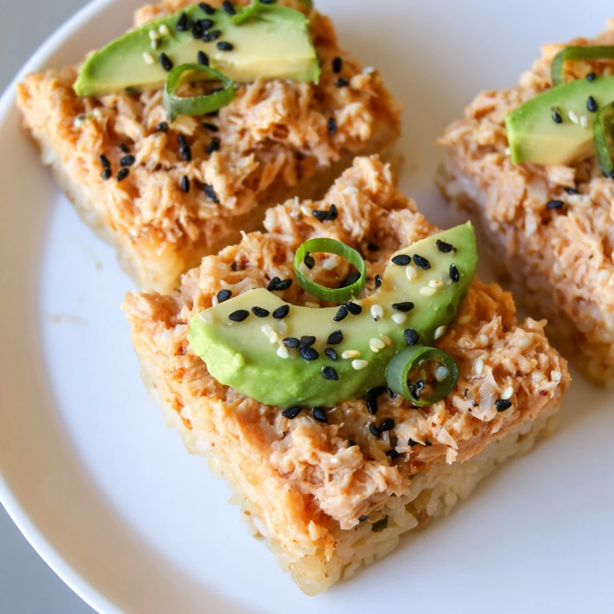 Golden, crispy Spicy Tuna Crispy Rice appetizers are topped with a vibrant, creamy tuna mixture.