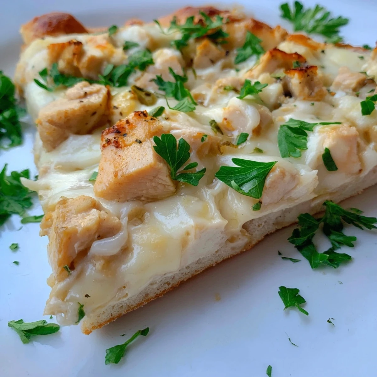 Slices of Chicken Alfredo Pizza display bubbly mozzarella, savory chicken, and a rich white sauce on a wooden board.