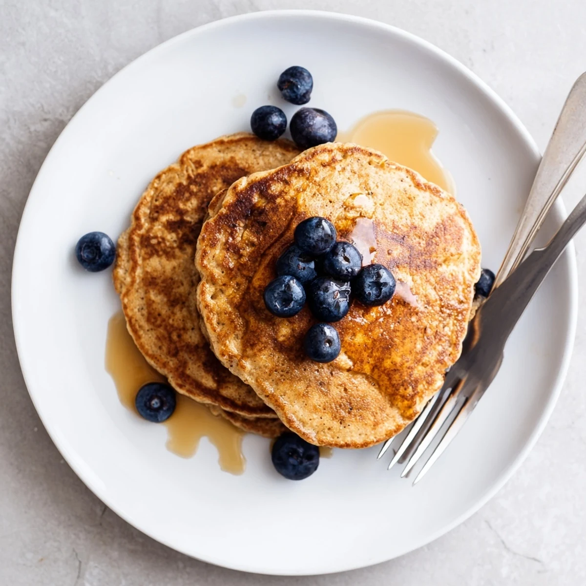 Fluffy Protein Power Pancakes stacked high, golden-brown and drizzled with maple syrup on a rustic plate.