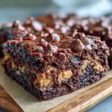 Serving suggestion for Rich Peanut Butter Cup Dump Cake: a warm wedge topped with vanilla ice cream melting over gooey peanut butter cups.