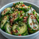 Vibrant cucumber slices tossed in sesame and rice vinegar dressing, garnished with sesame seeds and green onions.