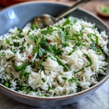 Spring Pea and Mint Rice Pilaf with vibrant green peas and fresh mint, served in a white bowl beside lemon wedges.