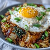 Savory kimchi fried rice bowl, bursting with vibrant flavors and topped with fresh garnishes.