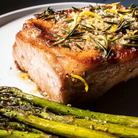 Juicy One-Pan Lemon Herb Pork Chops, surrounded by roasted asparagus and herbs, a delicious dinner.