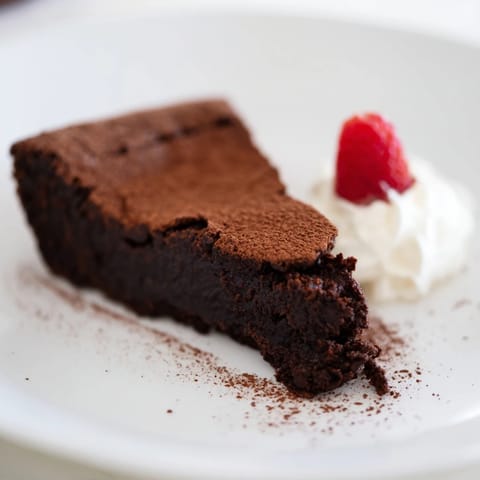 Rich, dark, and fudgy: serving a delicious flourless chocolate cake dusted in cocoa powder.