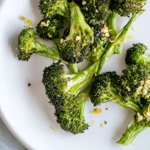A close-up view of perfectly roasted Lemon Garlic Roasted Broccoli, glistening from a fresh lemon drizzle.