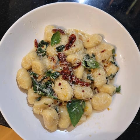 Picture a vibrant plate of creamy Tuscan gnocchi, garnished with fresh basil, ready to enjoy.