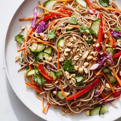 Chilled cold noodle salad with sesame-ginger dressing, featuring fresh veggies and crunchy toppings.