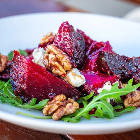 A close-up of a beautifully plated Roasted Beet Walnut Salad with fresh arugula and vinaigrette drizzled.