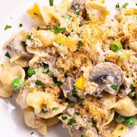 A close-up of creamy tuna noodle casserole with peas and crispy panko topping.