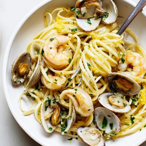 Close-up of Seafood Linguine featuring plump shrimp and mussels over al dente pasta, with a light lemon and white wine sauce.