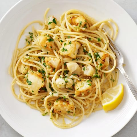 In this bowl, Crispy Fish Pasta combines al dente linguine with buttery garlic sauce, crispy fish, and zesty lemon garnish.  