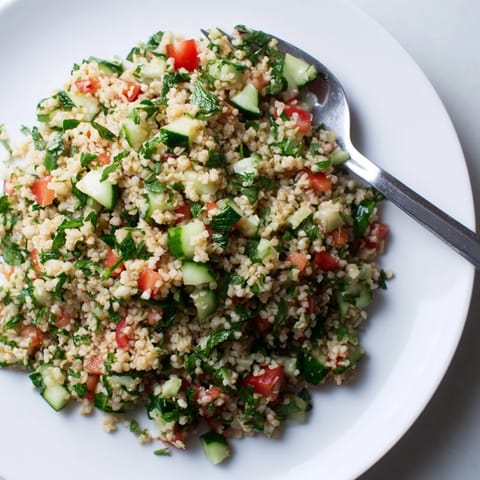 A colorful bowl of homemade bulgur wheat salad tabbouleh topped with zesty lemon dressing and mint.  