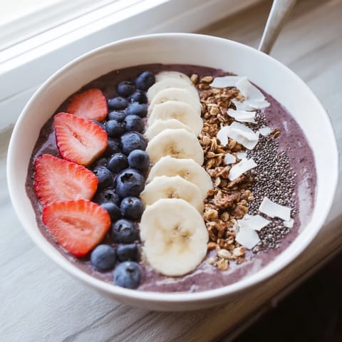 Colorful acai smoothie bowl topped with fresh berries, chia seeds, and coconut flakes, served chilled in a bowl.