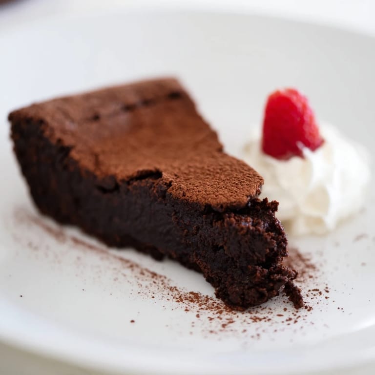 Rich, dark, and fudgy: serving a delicious flourless chocolate cake dusted in cocoa powder.