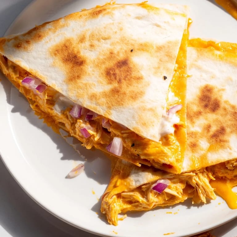 Delicious, cheesy Buffalo Chicken Quesadilla, cut into wedges and served with creamy ranch dressing.