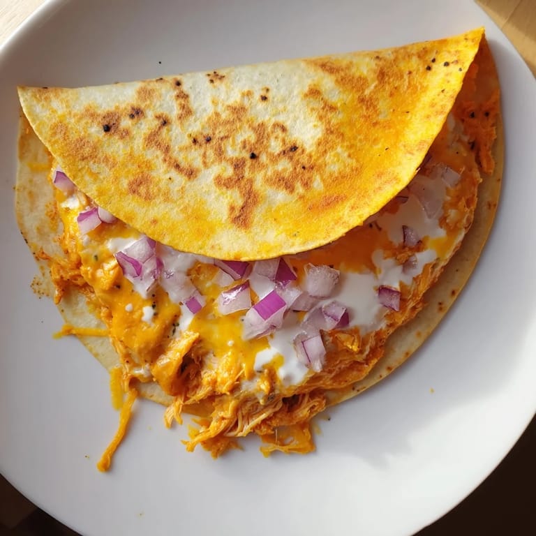 A close-up of a sizzling Buffalo Chicken Quesadilla, oozing cheese and perfectly folded.