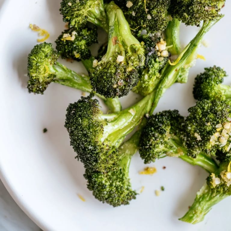 A close-up view of perfectly roasted Lemon Garlic Roasted Broccoli, glistening from a fresh lemon drizzle.