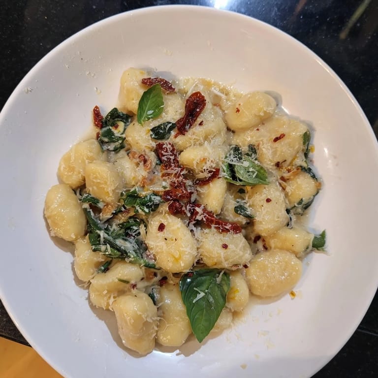 Picture a vibrant plate of creamy Tuscan gnocchi, garnished with fresh basil, ready to enjoy.