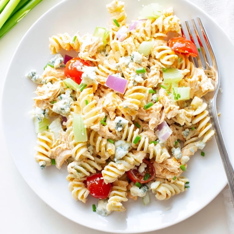 Colorful Buffalo Chicken Pasta Salad in a white serving bowl, ready to eat and loaded with buffalo chicken, tomatoes, and zesty ranch.