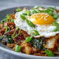 Spicy fermented cabbage kimchi fried rice bowl with a perfectly fried sunny-side-up egg.